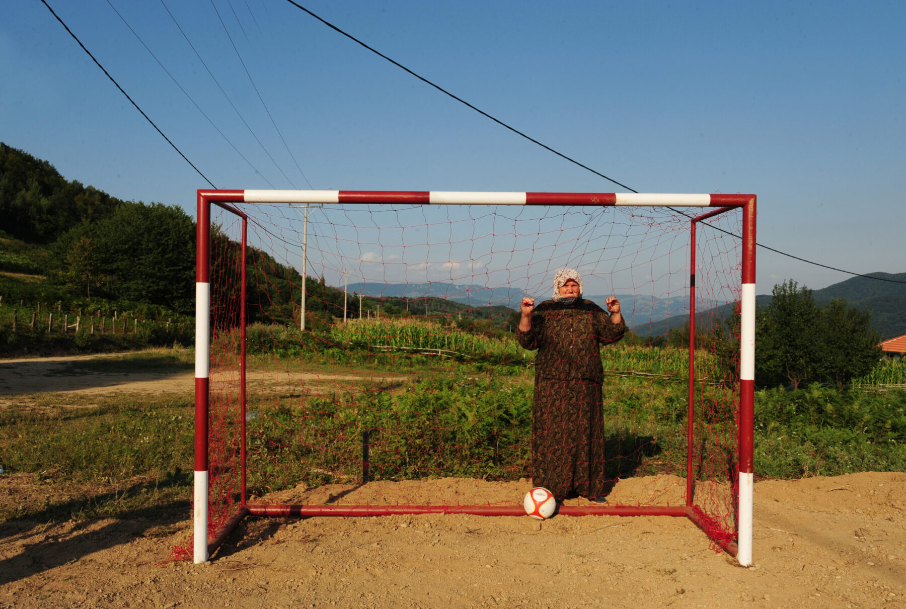 Bosnia, 15 years after the war. A Bosniak woman looks on at a newly refurbished football pitch in a mountain village which aims to help returning Bosniaks rebuild their shattered lives.