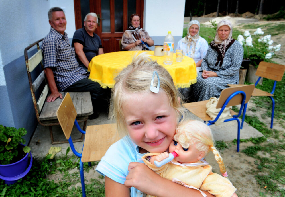 Bosnia, 15 years after the war. Bosniak muslim girl Amina Alic with her family and neighbours in a mountain village outside of Srebrenica. Her relatives would have been victims of the ethnic cleansing. Her innocent looks were a stark contrast to the prematurely aged pained expressions of her relatives who remember the atrocities.