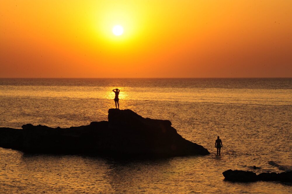Tripoli beach sunset. Under a burning red hot African sun Tripolitans cool down in the Mediterranean sea in Tripoli.